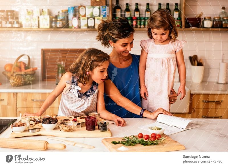 Little sisters cooking with her mother in the kitchen. Mother Child Girl Cooking Kitchen Tomato Pizza Vegetable Daughter Spread Day Happy Joy Family & Relations