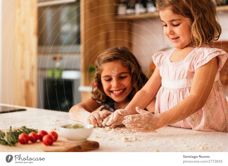 Little sisters kneading dough preparing for baking cookies. Child Girl Cooking Kitchen Flour Hand Dough Dirty stained Laughter Daughter Day Happy Joy Playing