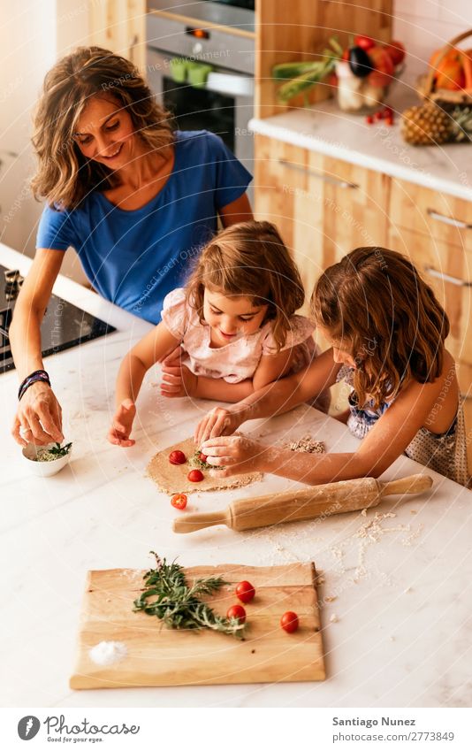 Little sisters cooking with her mother in the kitchen. Mother Child Girl Cooking Kitchen Tomato Pizza Vegetable Daughter Spread Day Happy Joy Family & Relations