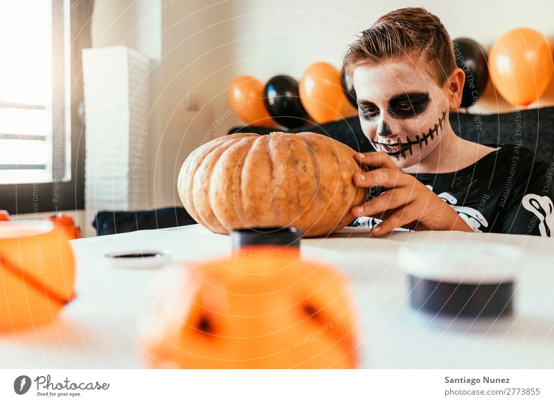 Happy boy disguised decorating a pumpkin at home. Hallowe'en Child Boy (child) Painting (action, artwork) Skeleton Joy Disguised Family & Relations Brother