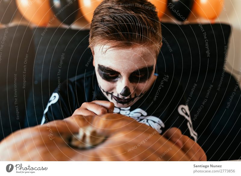 Happy boy disguised decorating a pumpkin at home. Hallowe'en Child Boy (child) Painting (action, artwork) Skeleton Joy Disguised Family & Relations Brother