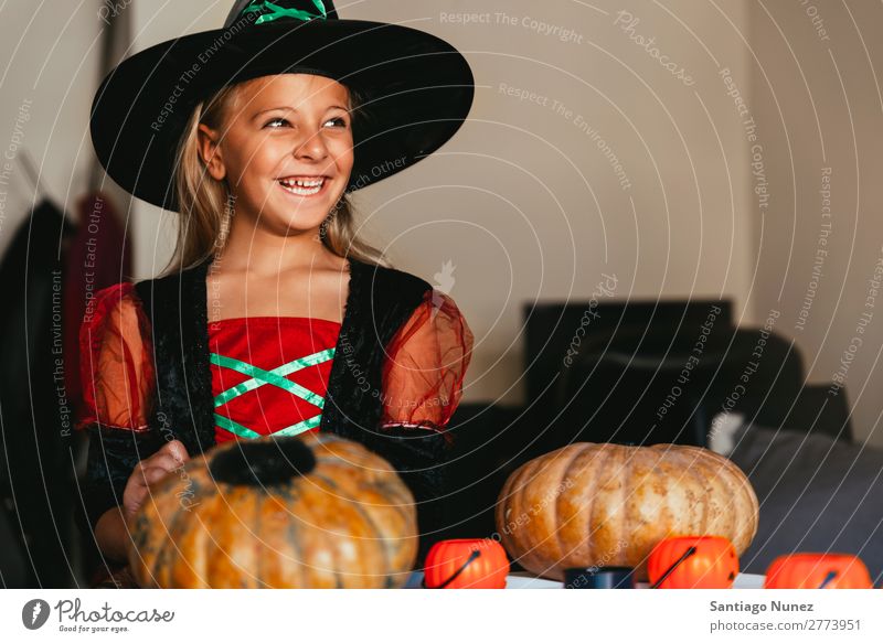 Beautiful girl disguised of witch decorating a pumpkin at home. Hallowe'en Child Girl Painting (action, artwork) Witch Disguised Joy Family & Relations Sister