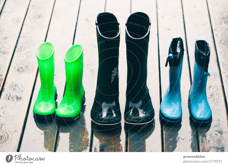 Row of wellies standing on a wooden porch while raining Joy Summer Child Human being Woman Adults Man Weather Rain Coat Footwear Boots Rubber boots Small Wet