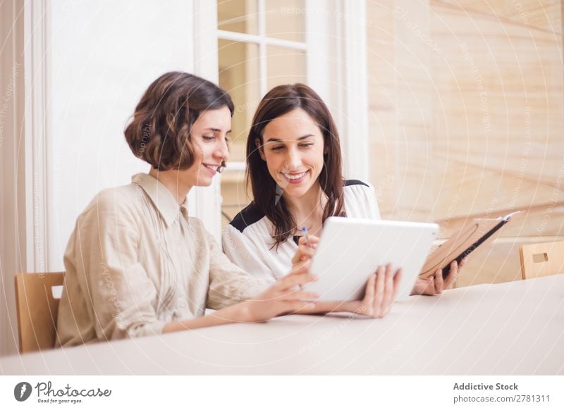 Young women looking at tablet and smiling Woman Smiling Tablet computer Communication Technology Cheerful Indicate using Business small business Entrepreneur