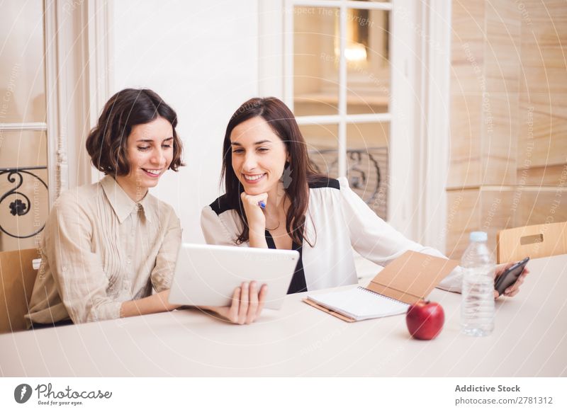 Young women looking at tablet and smiling Woman Smiling Tablet computer Communication Technology Cheerful Indicate using Business small business Entrepreneur