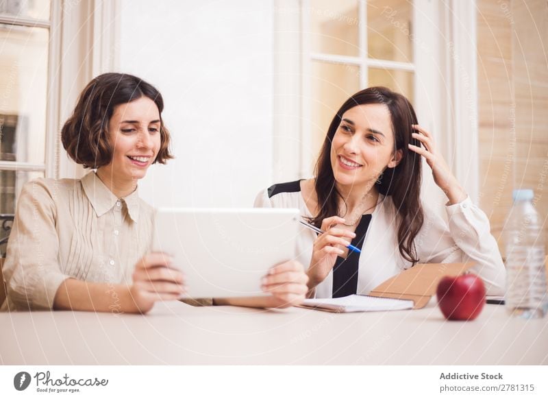 Young women looking at tablet and smiling Woman Smiling Tablet computer Communication Technology Cheerful Indicate using Business small business Entrepreneur