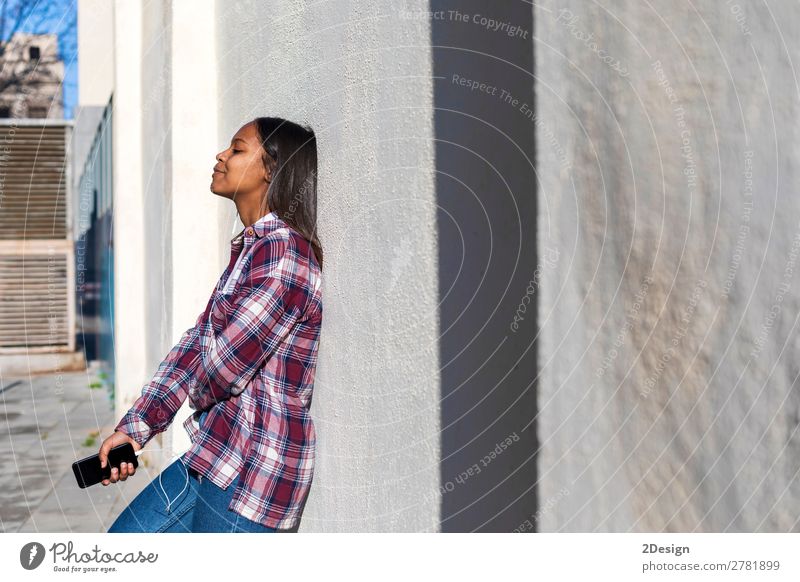 Beautiful young african american woman leaning on a white wall Lifestyle Style Music Telephone PDA Human being Feminine Young woman Youth (Young adults) Woman