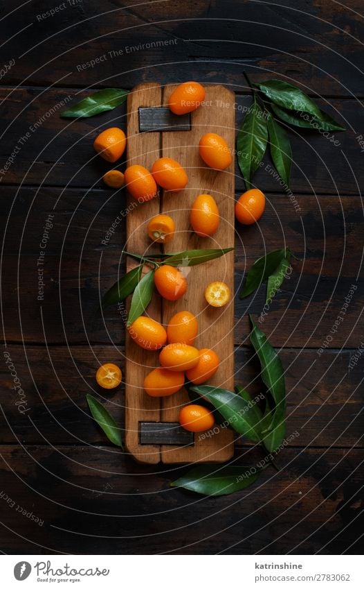 Kumquat fruits on a dark wooden background Fruit Dessert Nutrition Vegetarian diet Diet Exotic Group Leaf Dark Fresh Natural Above Juicy Brown Yellow Colour