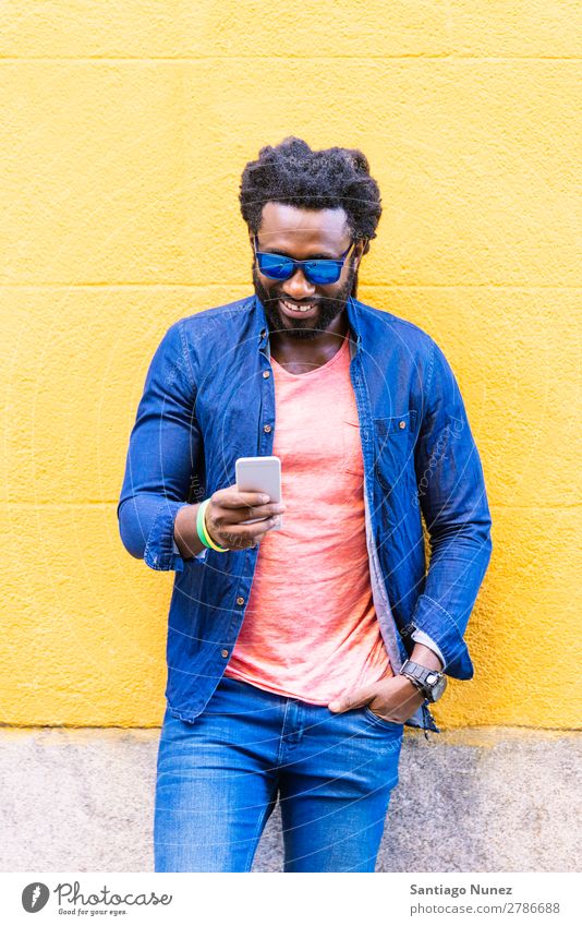 African Young Man Using Mobile In The Street. Lifestyle Listening Black American Town Portrait photograph Telephone PDA Solar cell Communication texting Email