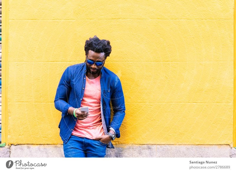 African Young Man Using Mobile In The Street. Lifestyle Listening Black American Town Portrait photograph Telephone PDA Solar cell Communication texting Email