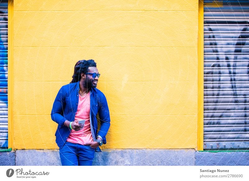 African Young Man Using Mobile In The Street. Lifestyle Listening Black American Town Portrait photograph Telephone PDA Solar cell Communication texting Email