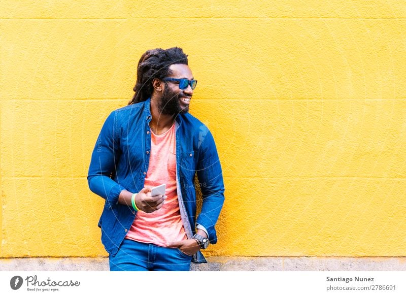 African Young Man Using Mobile In The Street. Lifestyle Listening Black American Town Portrait photograph Telephone PDA Solar cell Communication texting Email