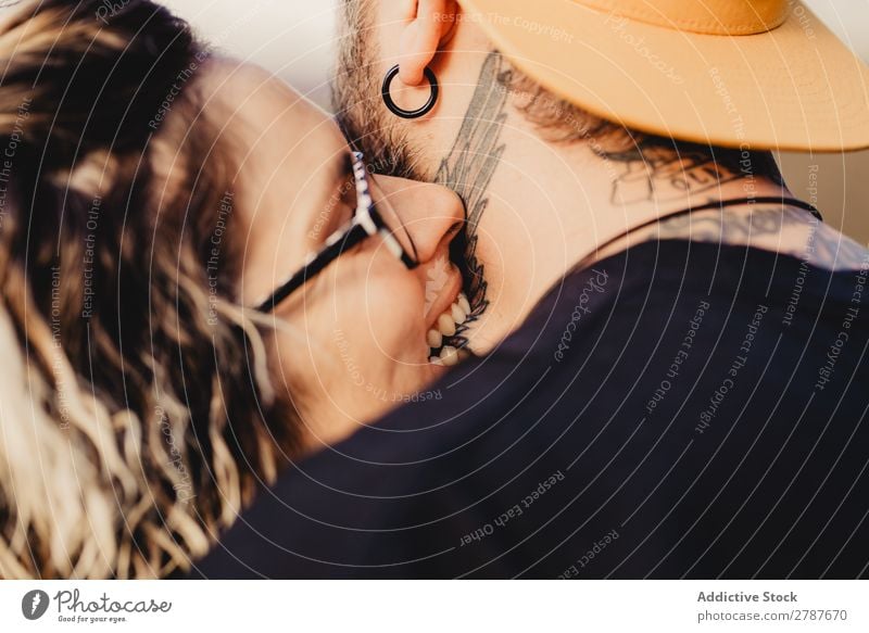 Young lady biting guy in tattoos Couple Tattoo Neck Eyeglasses Earring snapback Lady Guy Youth (Young adults) Hipster Man Woman embracing romantic Embrace Art