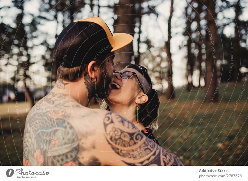 Young guy in tattoos hugging lady in forest Couple Tattoo Embrace Forest snapback Park Lady shirtless Guy Youth (Young adults) Hipster embracing Man Woman