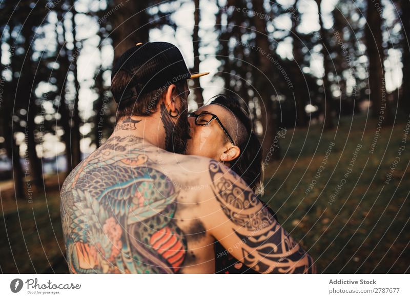 Young guy in tattoos hugging lady in forest Couple Tattoo Embrace Forest snapback Park Lady shirtless Guy Youth (Young adults) Hipster embracing Man Woman