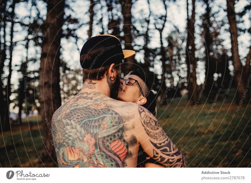 Young guy in tattoos hugging lady in forest Couple Tattoo Embrace Forest snapback Park Lady shirtless Guy Youth (Young adults) Hipster embracing Man Woman