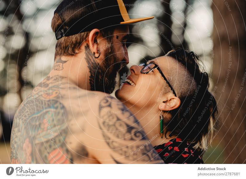 Young guy in tattoos hugging lady in forest Couple Tattoo Embrace Forest snapback Park Lady shirtless Guy Youth (Young adults) Hipster embracing Man Woman