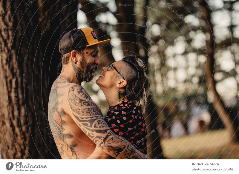 Young guy in tattoos hugging lady in forest Couple Tattoo Embrace Forest snapback Park Lady shirtless Guy Youth (Young adults) Hipster embracing Man Woman