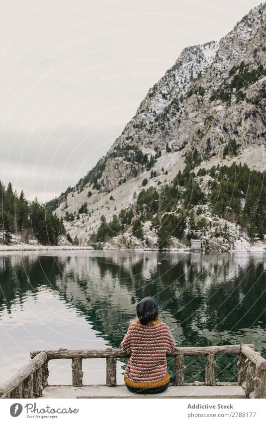 Woman on seat near wonderful lake between hills in snow and cloudy sky Lake Hill Seat Snow Pyrenees Sky Wonderful Water Surface Mountain Clouds Lady Height Tree