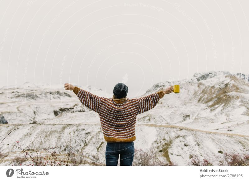 Young woman with cup and hands to sides between mountains Woman Mountain Cup Pyrenees Hand Side Lady Sweater Hat Hill Mug Snow Wonderful Youth (Young adults)