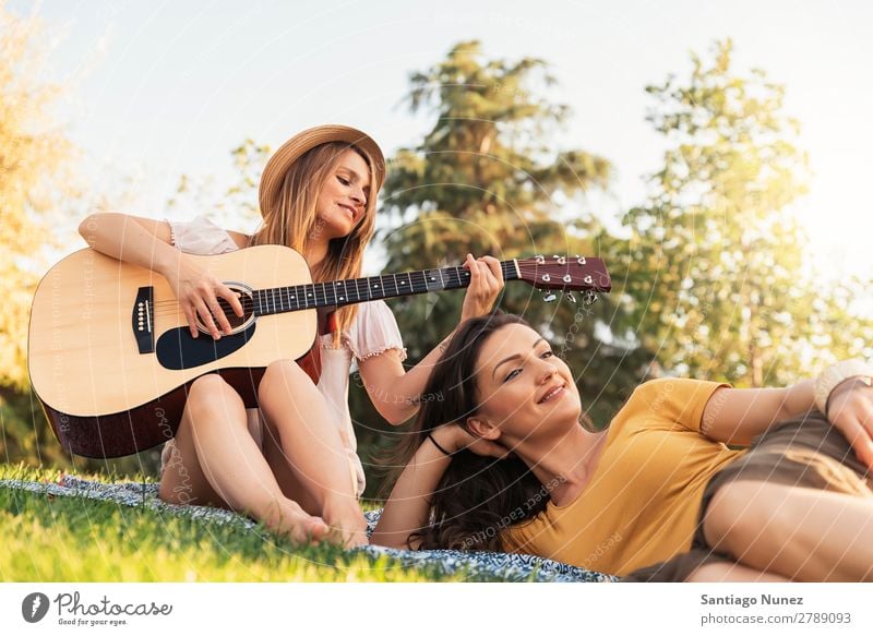 Beautiful women having fun playing guitar in the park. Woman Picnic Friendship Youth (Young adults) Park Happy Guitar Guitarist Summer Human being Joy Playing