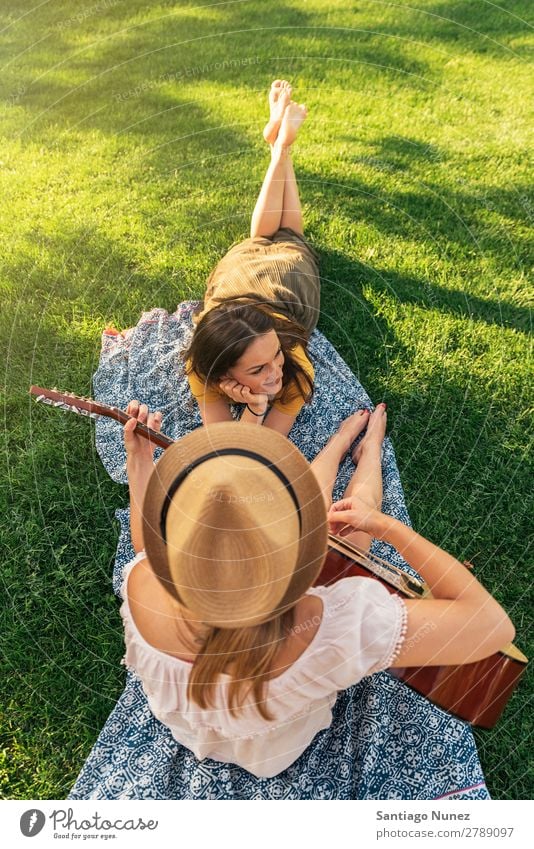 Beautiful women having fun playing guitar in the park. Woman Picnic Friendship Youth (Young adults) Park Happy Guitar Guitarist Summer Human being Joy Playing