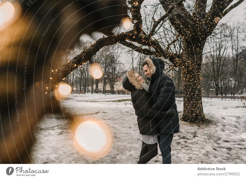 Smiling couple having fun on street near tree with fairy lights Couple Fairy lights Christmas & Advent Street Tree Guy Lady ski jacket Happy Hand Wood