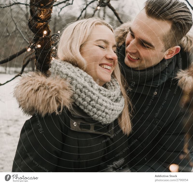 Smiling couple having fun on street near tree with fairy lights Couple Fairy lights Christmas & Advent Street Tree Guy Lady ski jacket Happy Laughter Wood