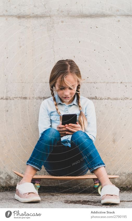 Kid using mobile phone with skate Screen Hold Technology Exterior shot Child Playing Digital Tablet computer Leisure and hobbies Hand device Joy Easygoing