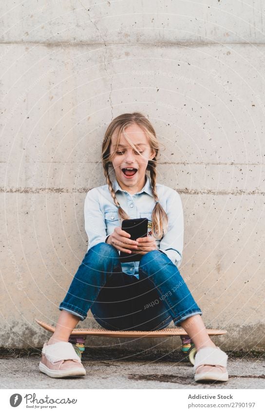 Kid using mobile phone with skate Screen Hold Technology Exterior shot Child Playing Digital Tablet computer Leisure and hobbies Hand device Joy Easygoing