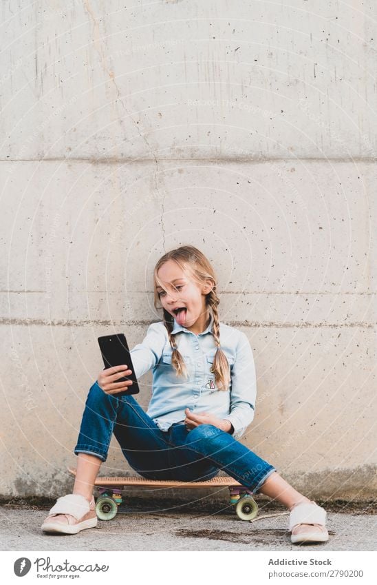 Kid using mobile phone with skate Screen Hold Technology Exterior shot Child Playing Digital Tablet computer Leisure and hobbies Hand device Joy Easygoing