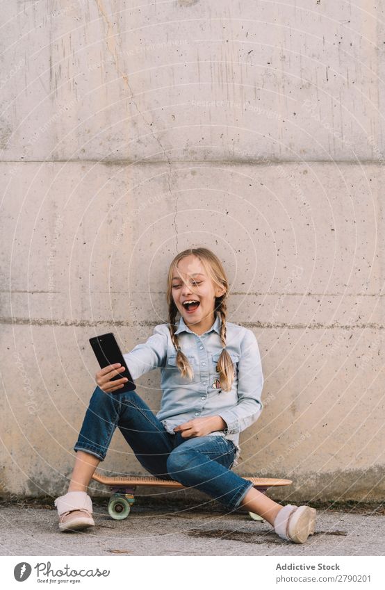 Kid using mobile phone with skate Screen Hold Technology Exterior shot Child Playing Digital Tablet computer Leisure and hobbies Hand device Joy Easygoing