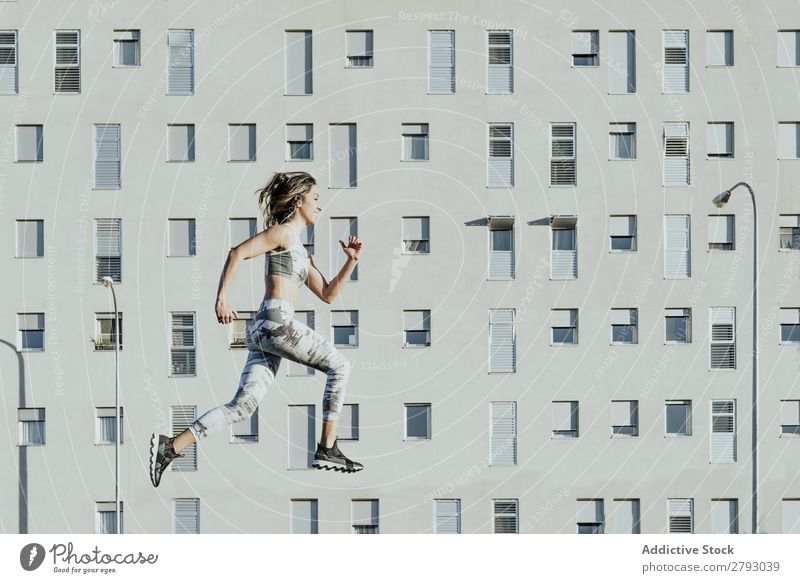 Woman in sportswear jumping near building Sports Jump Sportswear Building Athletic Sunbeam Weather Thin Lady levitating Flying Fitness Youth (Young adults)