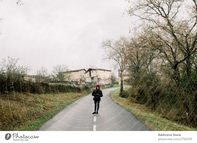 Woman in coat with camera on road Camera Street Coat orduna Spain Hand pocket Hat Winter Wear Lady Youth (Young adults) Landscape Lanes & trails