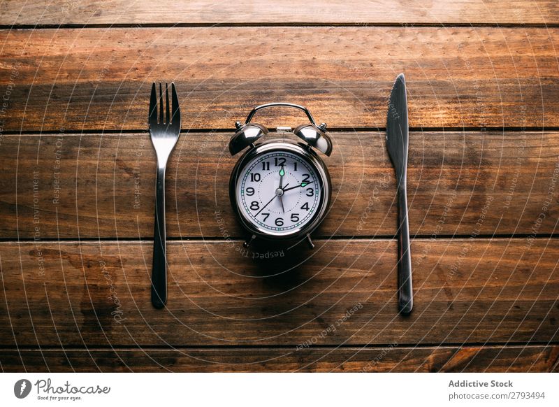 Cutlery near alarm clock Alarm clock Table Conceptual design Diet Fork Knives Time Meal Minute hand Hour hand Lunch Dinner Breakfast Mechanical Metal Style