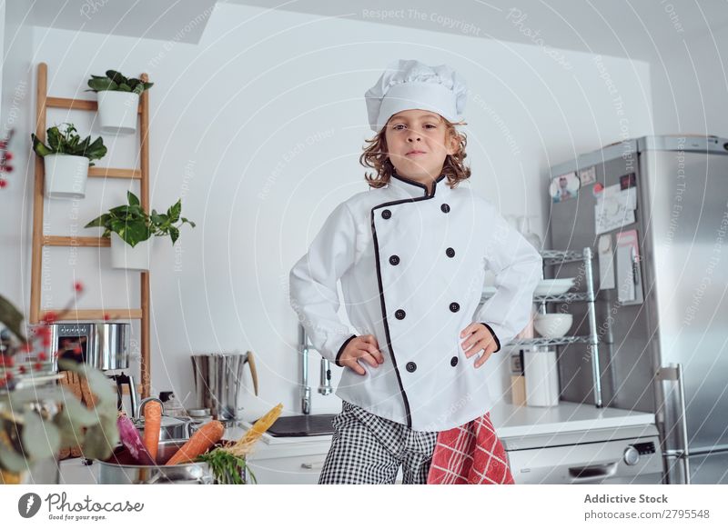 Boy in cook hat in kitchen Cook Boy (child) Kitchen Carrot chef Child Vegetable Hat Fresh Indicate Hand Hip Cooking Modern Funny Home Light preparing Happiness