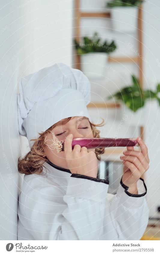 Boy in cook hat holding vegetable in kitchen Cook Boy (child) Kitchen Vegetable chef Child Hat smelling Closed eyes Fresh Cooking Modern Funny Home Light