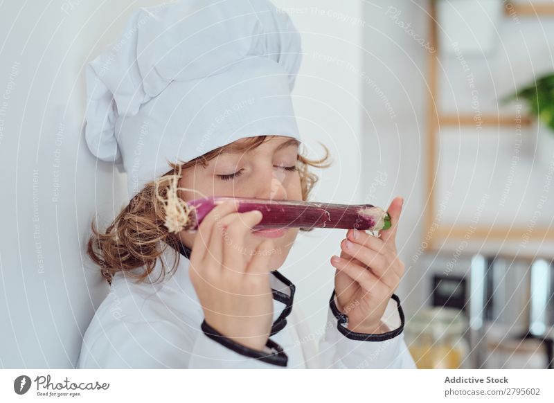 Boy in cook hat holding vegetable in kitchen Cook Boy (child) Kitchen Vegetable chef Child Hat smelling Closed eyes Fresh Cooking Modern Funny Home Light