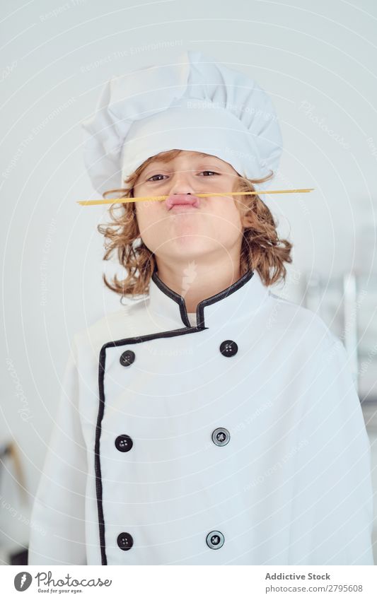 Boy in cook hat making moustache of macaroni in kitchen Cook Boy (child) Kitchen Moustache Macaroni chef Child Hat Pasta Dry Make Cooking Modern Funny Home