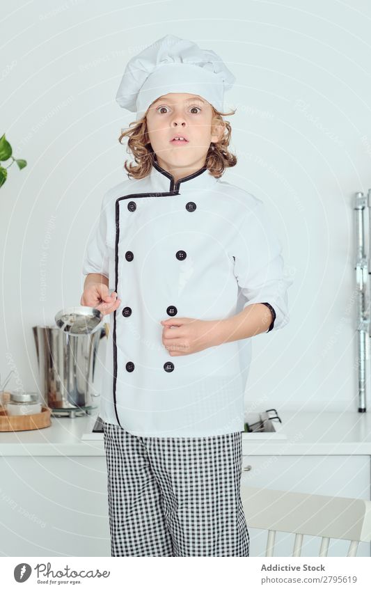 Boy in cook hat holding ladle and showing thumb up in kitchen Cook Boy (child) Kitchen Ladle chef Child Hat Cool (slang) Gesture Cooking Metal Modern Home