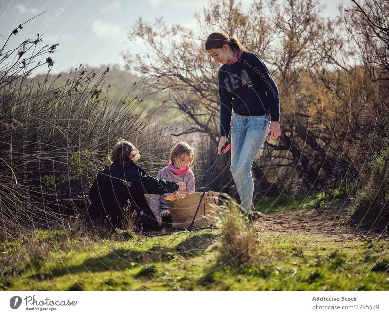 Lady and children putting garbage in basket in park Trash container Basket Park Ground Container Child Putt cleaning up Youth (Young adults) Environment