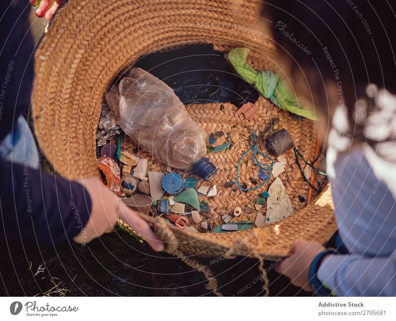 Person and children with heaps of garbage in hands near basket Trash container Heap Hand Basket Child Human being Accumulation Container Plastic cleaning up