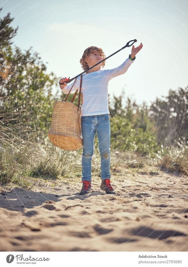 Boy with basket picking up garbage from ground Trash container Ground Child Basket litter picker Boy (child) Container cleaning up Field Shoulder Environment