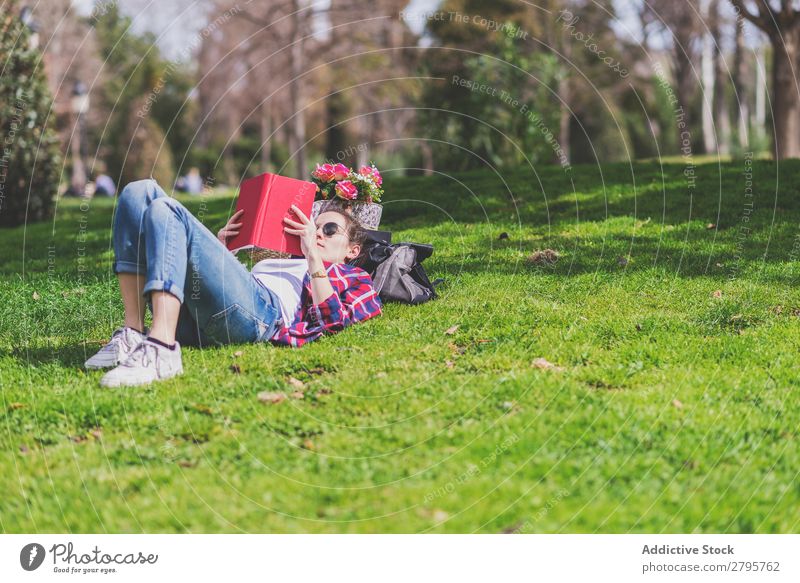 Side view of a hipster happy woman lying on grass in sunny day at park while reading a red book Profile Young woman Hipster Hip & trendy Lie (Untruth) Reading