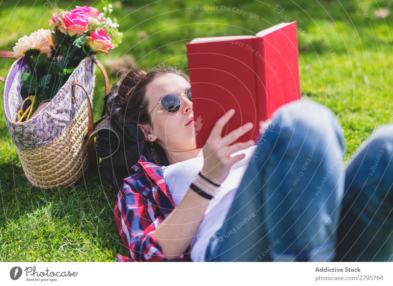 Side view of a hipster happy woman lying on grass in sunny day at park while reading a red book Profile Young woman Hipster Hip & trendy Lie (Untruth) Reading