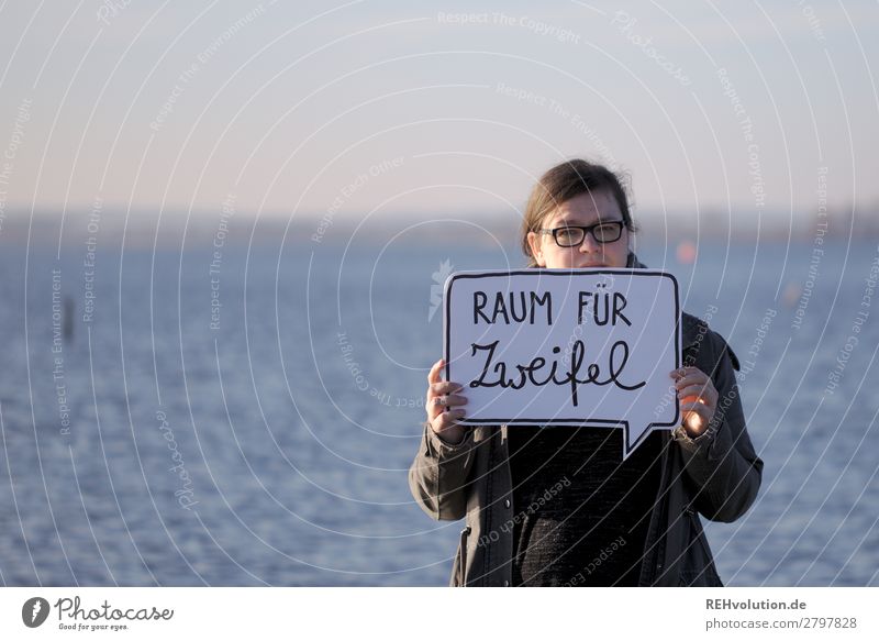 Woman stands by the water and holds a speech bubble on the subject of doubt Speech bubble Text Human being portrait Horizon Lake Nature To hold on Doubt God