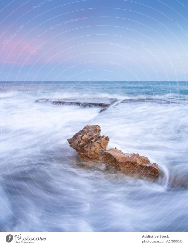 Amazing stones on shore near water and blue sky Coast Stone Water Sky Blue Clouds Fog Ocean Surface Sunset Heaven Rock Picturesque Vantage point Wonderful Foam