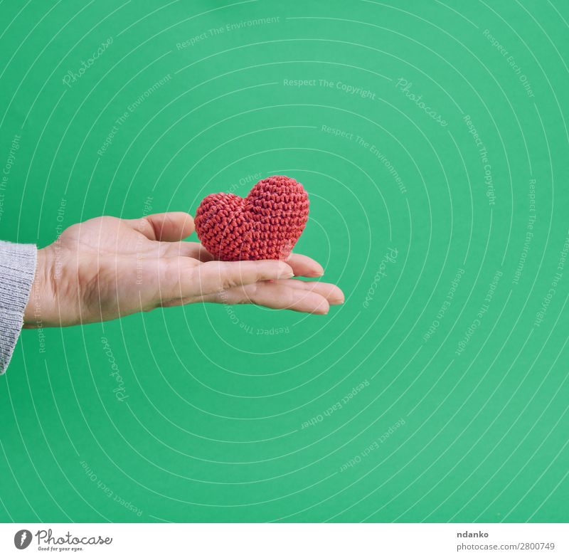 small knitted red heart in a human hand Decoration Feasts & Celebrations Valentine's Day Wedding Hand Heart Love Green Red Romance Colour background Card