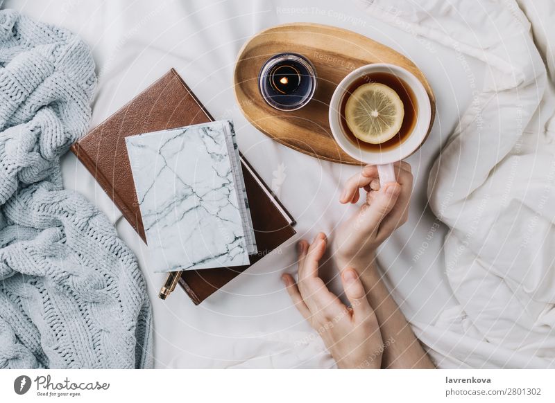 Woman's hands in bed holding lemon tea flat lay Hand holiday Knitted Bedroom Sweater Book Candle Lemon Cup Tea Lifestyle Mug Morning Notebook Top Vantage point