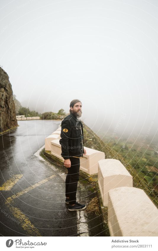 Anonymous man standing on cliff near countryside road Man Fog Landscape Street Cliff Spain playa norte Rock Vacation & Travel explore admiring Weather Trip